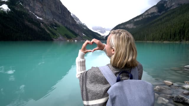Mujer-joven-haciendo-forma-marco-de-corazón-en-Lake-Louise