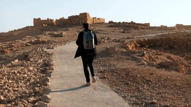Casual-European-tourist-walks-to-ancient-ruins.-Relaxed-man-on-summer-desert-road-takes-a-smartphone-photo.-Israel-4K