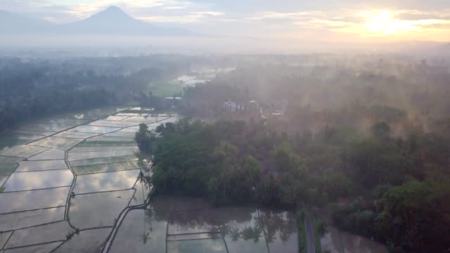 Tiro-de-drone-de-vista-aérea-de-la-ciudad-de-Borobudur-en-Java-en-sunrise,-viajes-Indonesia-religión-drone-concepto-4K-de-resolución-arrozales-y-volcán