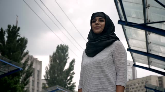 Joven-musulmana-hijab-está-esperando-la-estación-de-ferrocarril-n-lloviendo,-concepto-de-religión,-concepto-urbano.-concepto-de-tiempo,-vista-inferior