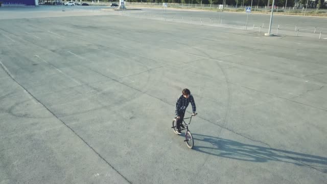 vista-del-joven-jinete-haciendo-piruetas-en-bicicleta-bmx-en-la-calle-urbanita-en-superficie-de-asfalto-de-vuelo