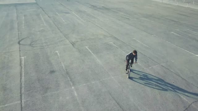 flying-view-of-young-rider-doing-tricks-on-bmx-bike-in-the-urban-street-on-asphalt-surface