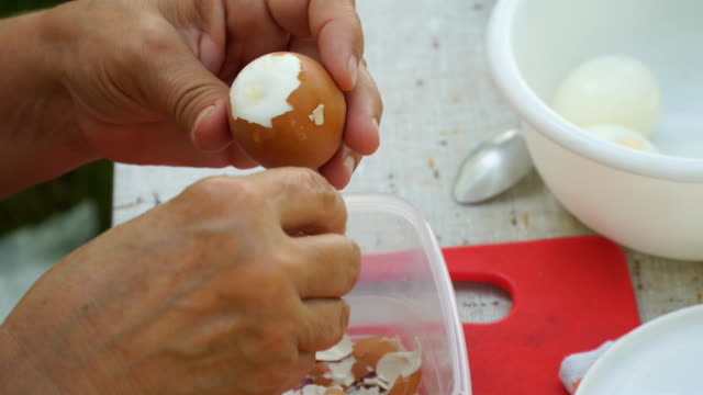 Eine-Frau-reinigt-ein-gekochtes-Hühnerei-von-shell