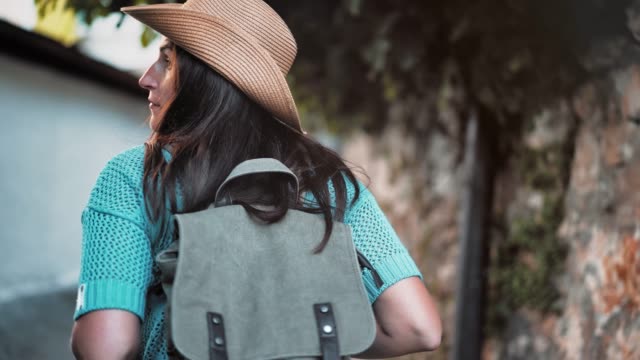 Steadicam-establish-shot-rear-view-backpacker-tourist-woman-enjoying-walking-narrow-street
