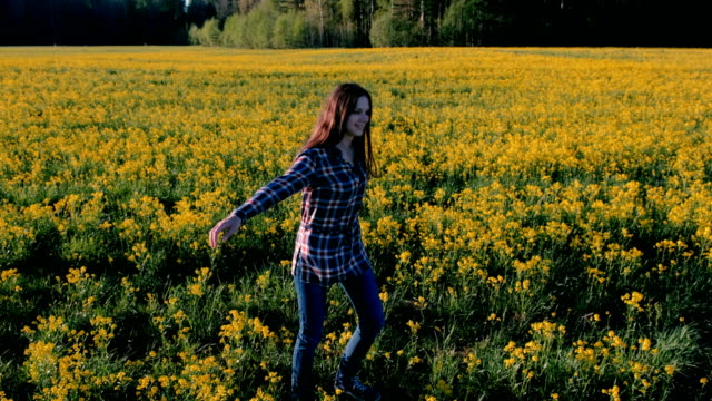 Brünette-Frau-dreht-sich-mitten-auf-einem-Feld-mit-gelben-Blüten.