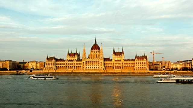 Cruise-ships-and-ferries-in-the-evening-at-the-Danube-river-in-Budapest,-Hungary.-day-to-night-time-lapse