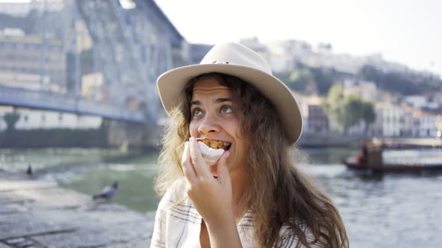 Young-girl-eating-egg-tart-on-embankment