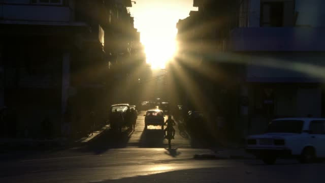 golden-hour-sun-rays,-old-classic-American-1950's-Vintage-car-drive-on-street-in-old-Havana-neighborhood,-Cuba