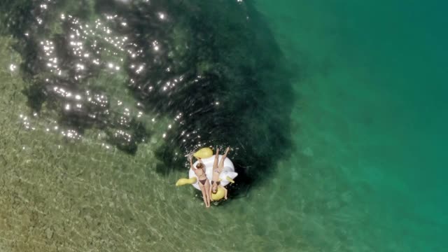 Aerial-view-of-two-women-floating-on-inflatable-in-Panagopoula,-Greece.