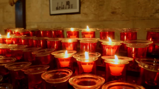 Reihen-brennender-Kerzen-in-roter-Form-in-einer-Kirche-in-Spanien