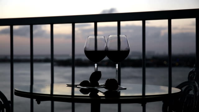 Romantic-evening-with-red-wine-on-balcony--at-sunset