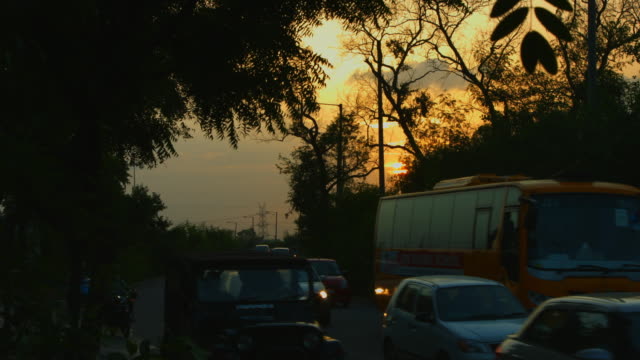 Bloqueada-on-shot-de-movimiento-de-tráfico-por-carretera-al-atardecer,-Delhi,-India