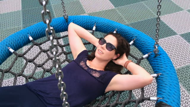Woman-in-her-thirties--(30s)-daydreaming-about-life-on-a-swing-in-the-playground