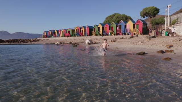 Junge-läuft-in-Richtung-Kamera-im-St-James-beach,-Kapstadt,-Südafrika