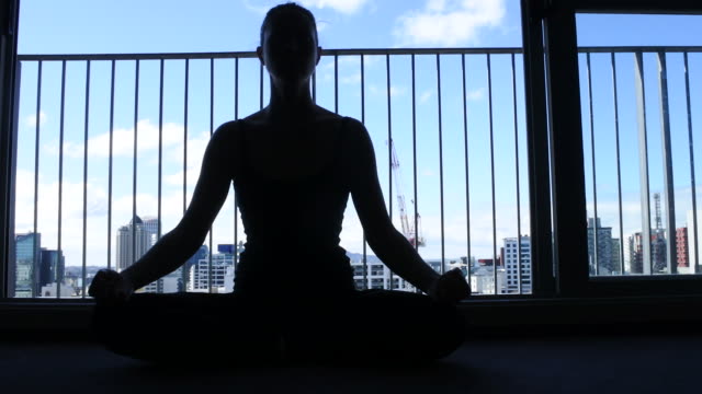 Woman-silhouette-sitting-on-floor-meditate