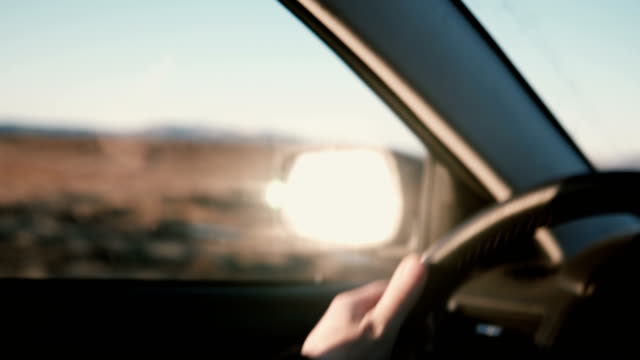 View-inside-the-car-on-countryside-desert-road-inbeautiful-sunset.-Close-up-view-of-male-hands-on-wheel