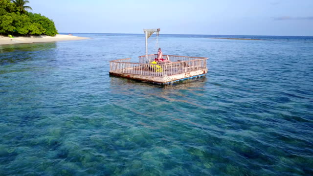v03849-fliegenden-Drohne-Luftaufnahme-der-Malediven-weißen-Sandstrand-2-Personen-junges-Paar-Mann-Frau-entspannend-auf-sonnigen-tropischen-Inselparadies-mit-Aqua-blau-Himmel-Meer-Wasser-Ozean-4k-schwimmenden-Ponton-Steg-Sonnenbaden-zusammen