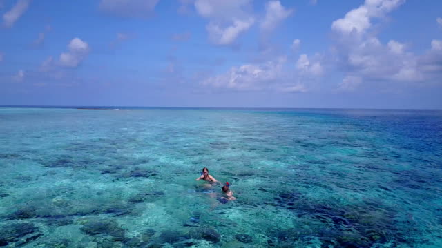 v04066-fliegenden-Drohne-Luftaufnahme-der-Malediven-weißen-Sandstrand-2-Personen-junges-Paar-Mann-Frau-Schnorcheln-Schwimmen-Tauchen-auf-sonnigen-tropischen-Inselparadies-mit-Aqua-blau-Himmel-Meer-Wasser-Ozean-4k