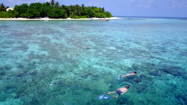 v04059-vista-aérea-de-drone-volando-de-Maldivas-playa-2-personas-pareja-joven-hombre-mujer-snorkel-natación-buceo-en-la-isla-de-paraíso-tropical-soleado-con-cielo-azul-aqua-agua-mar-4k