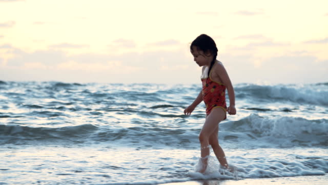 Little-girl-playing-on-the-beach-in-the-water-during-sunset-hour