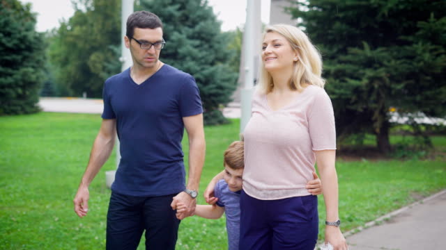 Fröhliche-Mutter-und-Vater-mit-kleinen-Sohn-zu-Fuß-auf-Park-im-Sommer