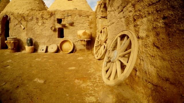 ruedas-de-madera,-antiguos-utensilios-y-casa-de-arcilla-en-la-aldea-árabe,-cerca-de-la-frontera-entre-Turquía-y-Siria