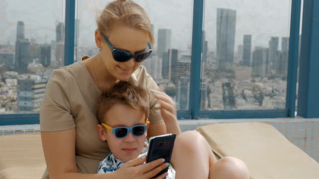 Mutter-und-Kind-mit-mobilen,-wenn-Erholung-am-Dach-des-Hotels-in-Tel-Aviv,-Israel