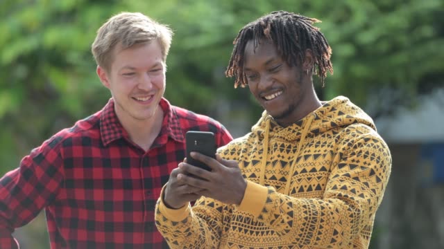 Multi-ethnischen-Jugendliche-mit-Handy-zusammen-in-den-Straßen-im-freien