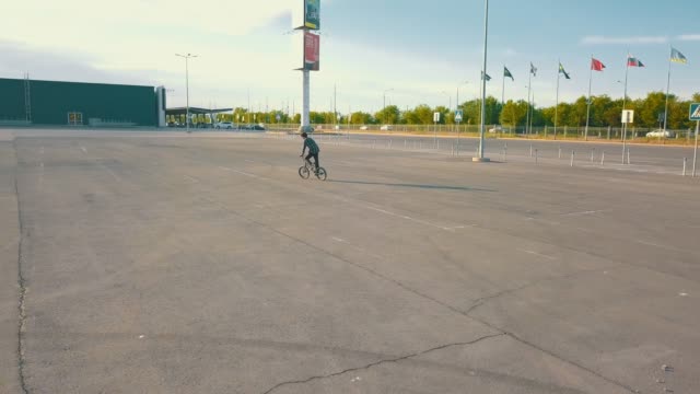 flying-camera-of-young-male-teenager-rider-on-the-bmx-bicycle-on-the-empty-urban-spot-no-people-asphalt