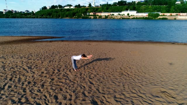 Woman-doing-yoga-on-the-beach-by-the-river-in-the-city.-Beautiful-view.