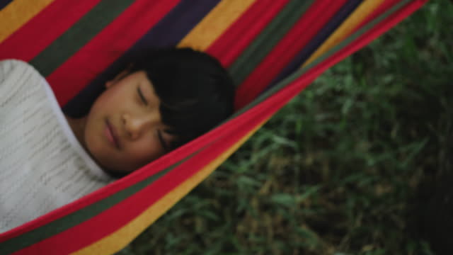 Little-girl-resting-lying-on-hammock-outdoors-in-slow-motion