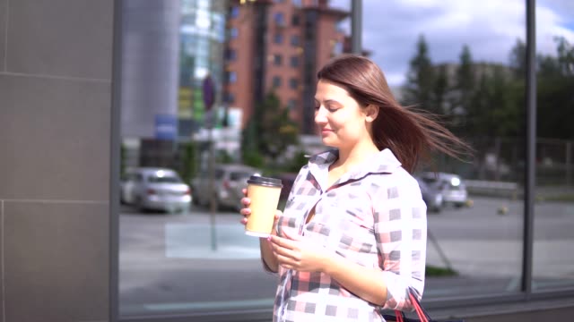 Young-girl-goes-after-shopping-with-bags-in-her-hands-drinking-coffee.-4K