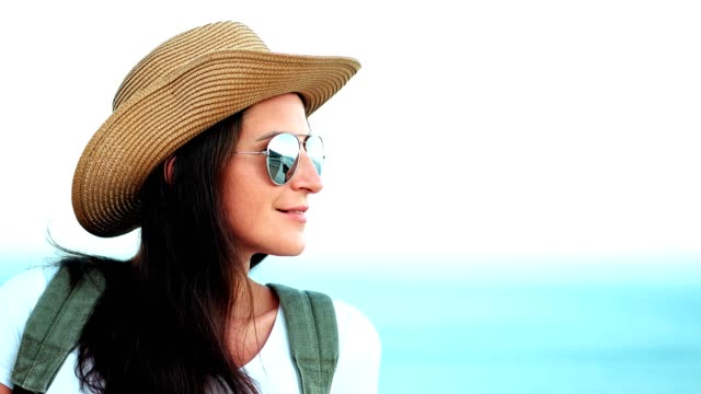 Porträt-der-nachdenkliche-junge-Frau-mit-Sonnenbrille-und-Hut-mit-Rucksack-erstaunliche-seelandschaft-genießen