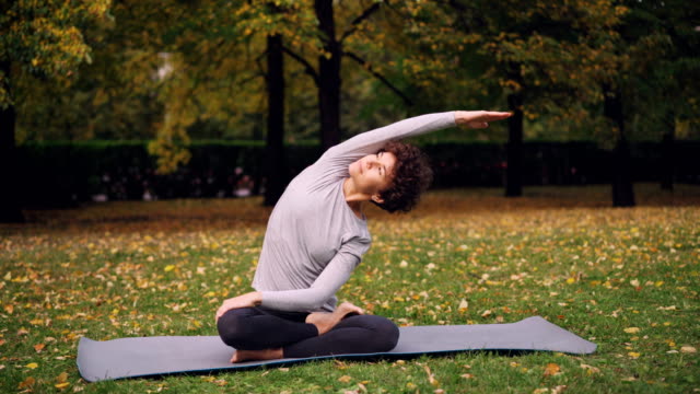 Schlanke-Mädchen-tut-Yoga-Übungen-für-gesunde-Wirbelsäule,-stretching,-Körper-und-Arme-dann-Entspannung-im-Lotus-Position-mit-den-Händen-auf-Kness-und-geschlossenen-Augen.-Jugend-und-Meditation-Konzept.