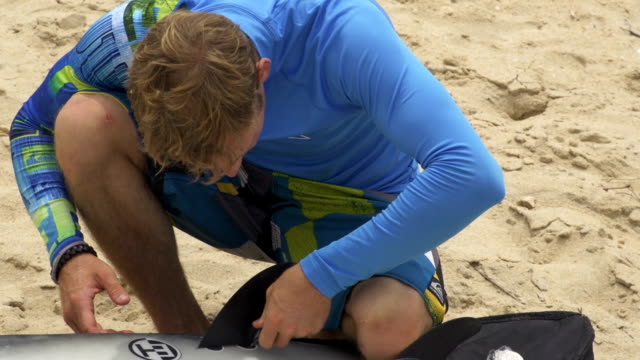 Young-surfer-inserting-fins-into-the-surfboard