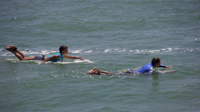SLOW-MOTION:-Surfer-boy-and-girl-paddling