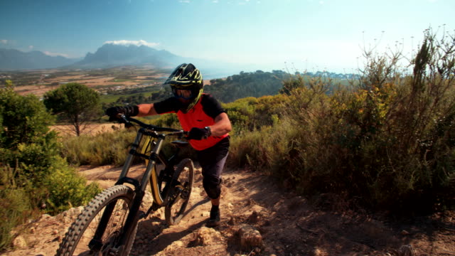 Mountain-biker-pushing-his-bike-over-rough-terrain