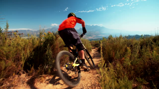 High-angle-view-of-mountain-biker-riding-a-dirt-path-downhill