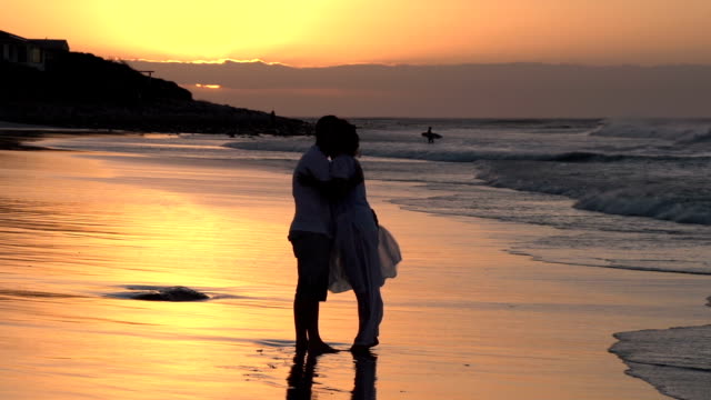 Couple-enjoying-romantic-embrace-on-the-beach-in-silhouette,South-Africa