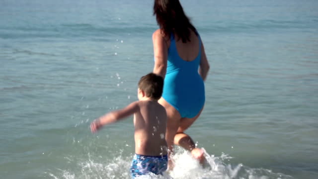 Joven-madre-y-niño-jugando-en-el-agua-en-la-playa,-plana-de-Cape-Town