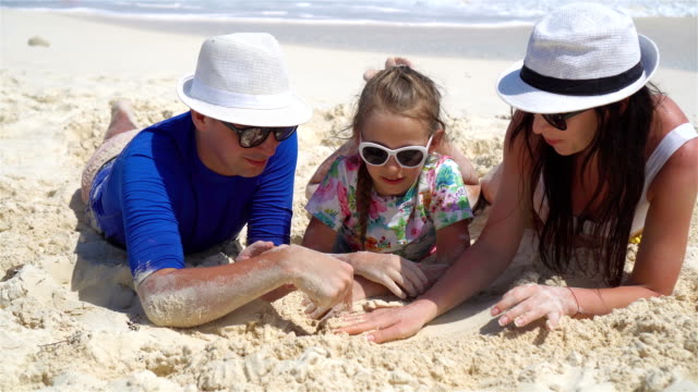 Junge-Familie-mit-drei-auf-dem-Sand-am-Strandurlaub
