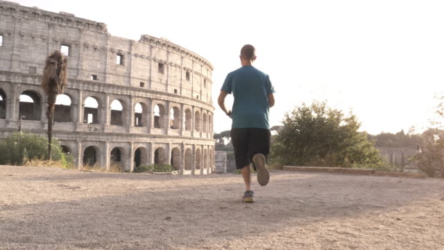 Hombre-en-ropa-deportiva-de-conducción-y-la-parada-en-una-colina-frente-al-Coliseo-de-Roma-al-atardecer
