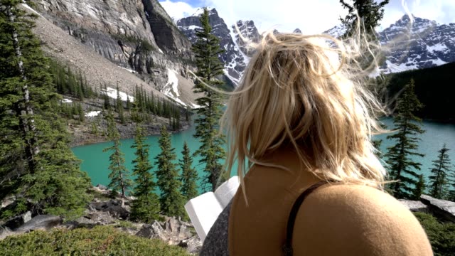 Libro-de-lectura-de-mujer-joven-en-el-lago-de-la-montaña
