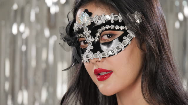Sexy-woman-wearing-masquerade-mask-flirting-at-party-over-silver-glitter-background,-slow-motion