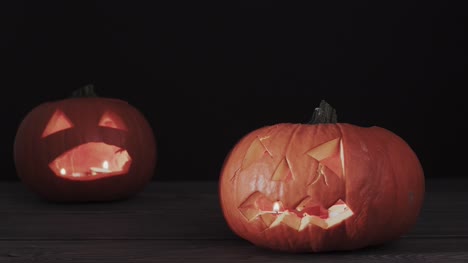 Zwei-Halloween-Kürbisse-mit-Furcht-einflössenden-Gesicht-auf-dem-Holztisch
