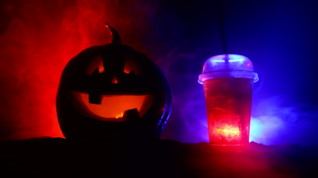 Halloween-Kürbis-orange-Cocktails.-Festliche-trinken.-Halloween-Party.-Lustige-Kürbis-mit-einem-glühenden-cocktail-Glas-auf-einem-dunkel-getönten-nebligen-Hintergrund.-Selektiven-Fokus