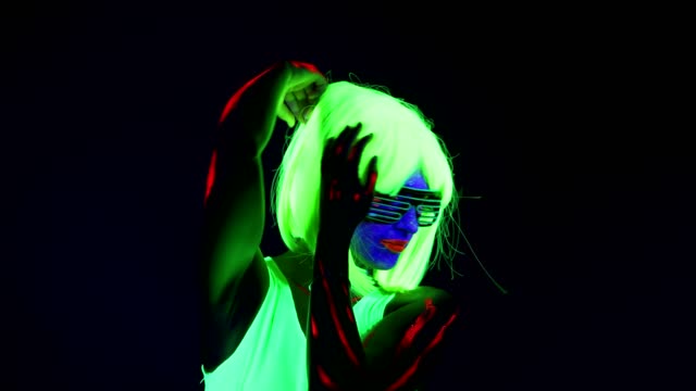 Woman-with-UV-face-paint,-wig,-glowing-glasses,-clothing-dancing.-Caucasian-woman.-.