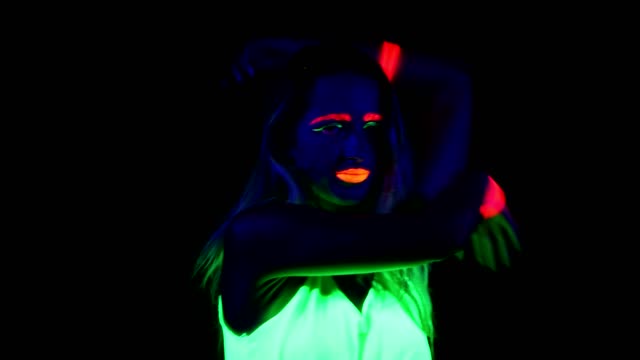 Frau-mit-UV-Gesicht-malen,-leuchtende-Kleidung,-leuchtende-Armband-tanzen-vor-der-Kamera.-Kaukasische-Frau.-.
