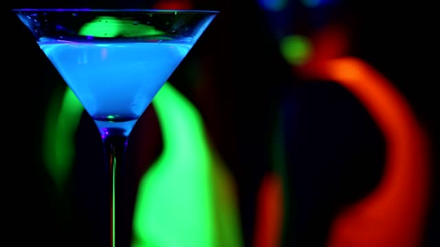 Blau-leuchtende-Drink-mit-tanzenden-Frauen-in-UV-Leuchten-Partei-Hintergrund.-.