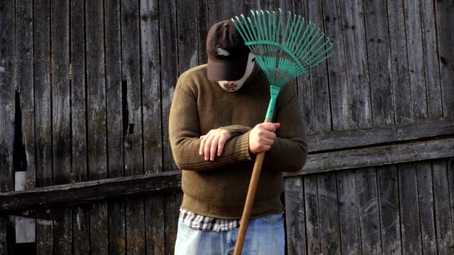 Man-in-a-Halloween-mask-with-a-rake-at-the-old-barn-wall